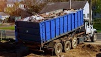 a blue dump truck is parked on a dirt road