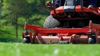 a man riding a lawn mower on a grassy field